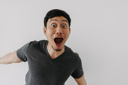 Funny surprised shocked asian man face for promotion isolated on background.の写真素材