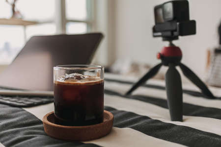 Black coffee on content creator desk with tripod camera and laptop.の写真素材