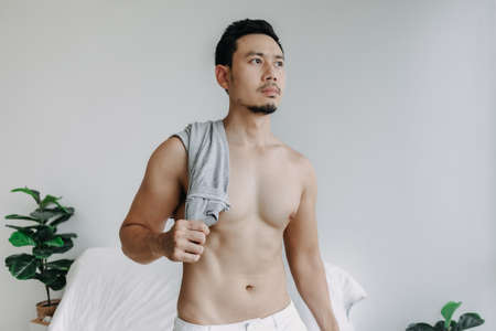 Asian man not wearing top relax after bath in the living room in his apartment.の写真素材