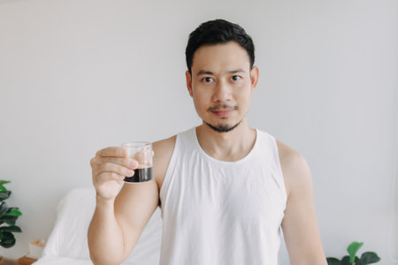 Asian man dink a shot of espresso coffee in his house for a fresh morning.の写真素材
