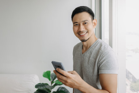 Young happy smiling asian man using smartphone feel relax and comfortable.の写真素材