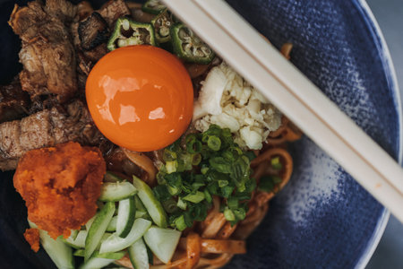 Hongkong style noodle with fresh raw egg and some vegetables served in a bowl.の写真素材