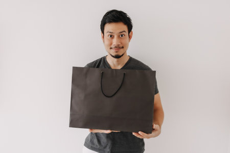 Asian man advertising black shopping back isolated on white background.