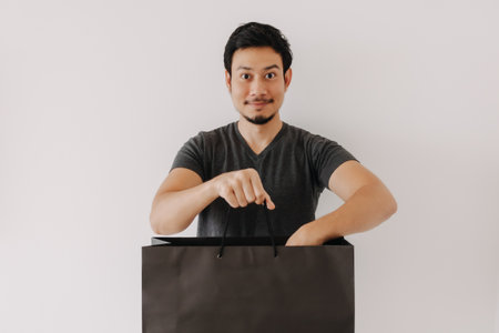 Asian man advertising black shopping back isolated on white background.の写真素材