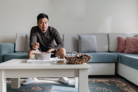 Lonely Asian man having a meal alone in his home.の写真素材