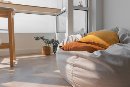 White beanbag with yellow and orange pillows in the corner of living room.の写真素材