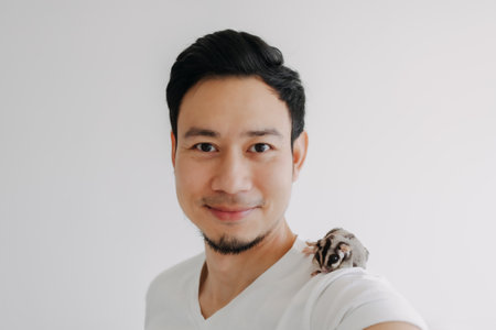 Happy Asian man with his pet Sugar Glider on his shoulder.の写真素材