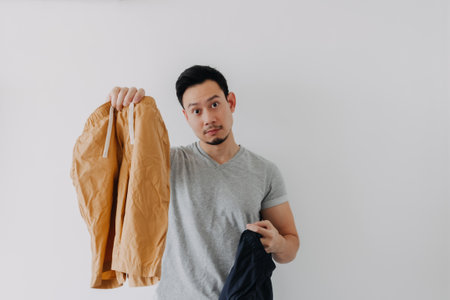 Asian man choosing a new short pants to wear isolated on white.