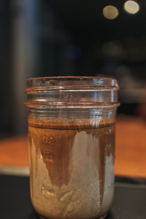 Close up dirty coffee in transparent glass served on black tray in the cafe.