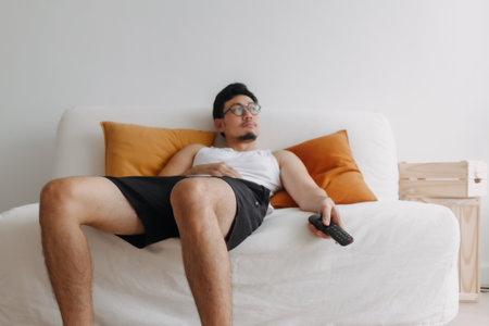 Boring life and lonely Asian man watching tv in his living room.の写真素材