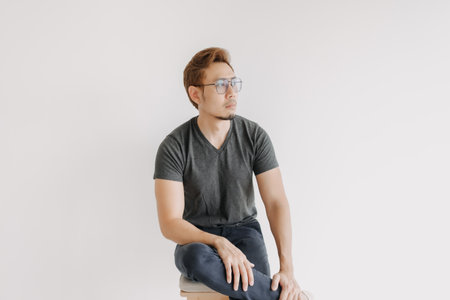 Cool Asian man gangster style sitting in black t-shirt isolated on white.