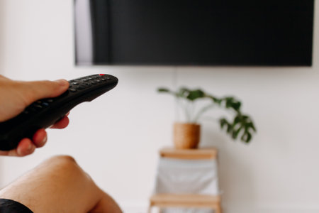 Hand holding remote point at the tv. Concept of watching tv,の写真素材