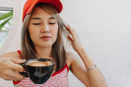 Cute asian girl in red drink hot coffee in the black cup.の写真素材