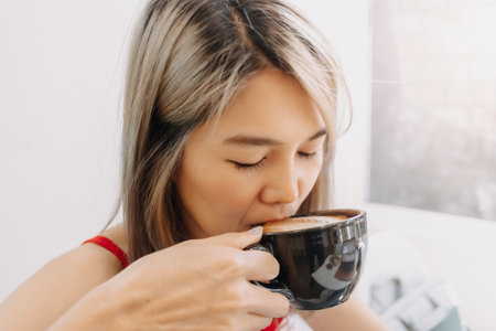 Cute asian girl in red drink hot coffee in the black cup.の写真素材
