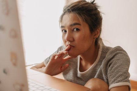 Serious asian woman working with her laptop in the bedroom.の写真素材