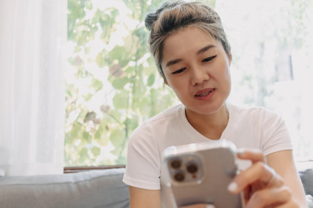 Asian cute girl texting on the phone while having a dessert in the cafe.の写真素材