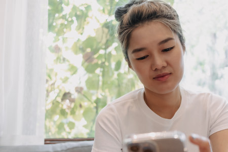 Asian cute girl texting on the phone while having a dessert in the cafe.