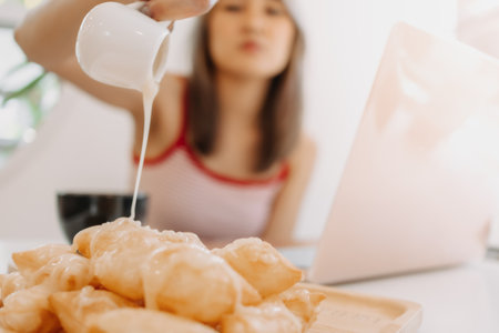 Asian girl pouring condensed milk onto fried doughs in the cafe.の写真素材