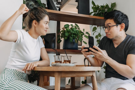Bad asian couple date of man addicted to mobile game and woman gets mad.の写真素材