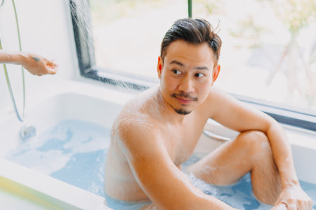 Happy childish disable asian man being take care of showering by his wife.