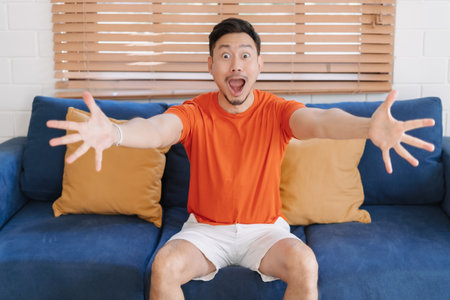 Wow and shocked face of asian man sit on the sofa in his home.の写真素材