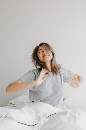 Portrait of asian woman just wake up and stretching on the bed in the morning.の写真素材