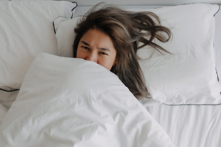 Top view of asian woman just wake up lying on the bed feeling not ready. High quality photo