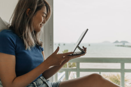 Happy freelance asian woman work on tablet on the hotel bed on travel trip.