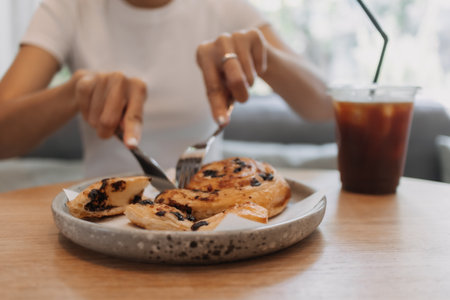 Woman is eating kind of dessert bread in the cafe.の写真素材