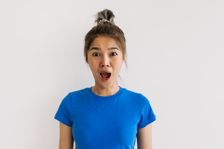 Shocked funny asian face of woman feeling unbelievable isolated on white.の写真素材