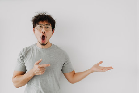 Bored face asian man presenting advertisement shocked mouth isolated on white.の写真素材