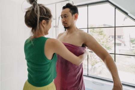 Funny and playful asian couple, wife helping husband after taking bath.の写真素材
