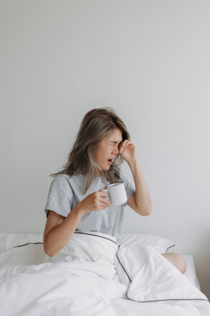 Asian woman hold a cup of coffee in white bedroom morning with empty space.の写真素材