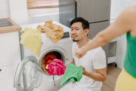 Funny crying face reaction of asian husband being forced to wash clothes by wifeの写真素材