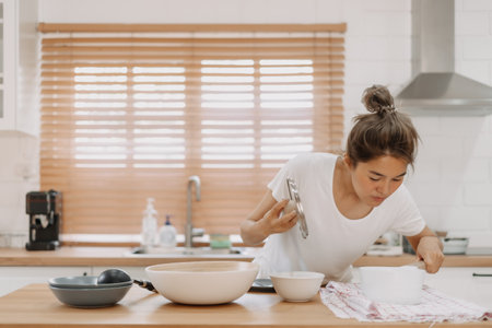 Asian woman checking out the food she made in the kitchen.の写真素材