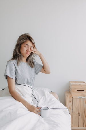 Asian woman hold a cup of coffee in white bedroom morning with empty space.の写真素材