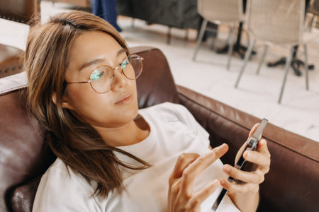 Bored asian woman using smartphone boringly in the cafe.の写真素材
