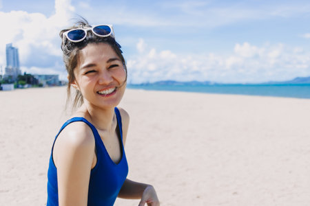 Happy smile asian woman in blue dress walking on the sunny beach of Pattaya.の写真素材