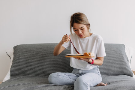 Asian woman concentrate on eating breakfast on the sofa. Concept of easy life.の写真素材