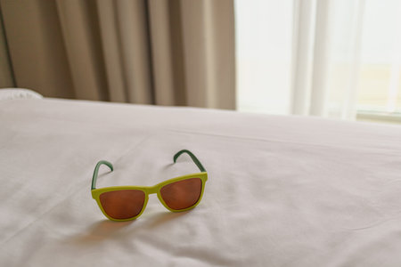 Sunglasses left on the bed in the hotel. Concept of traveling and vacation. High quality photoの写真素材