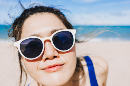 Close up face of happy asian woman in bright sunny beach in concept of skincare.の写真素材