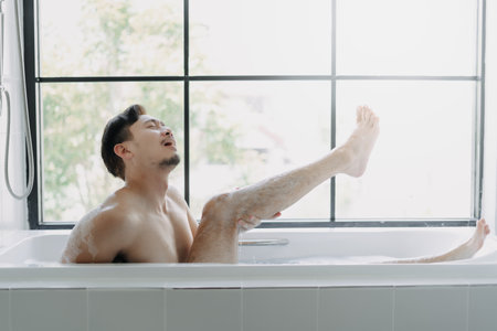 Funny asian man lying in the bathtub showing his leg pretend to be a sexy woman.