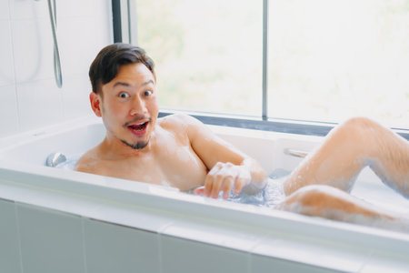 Funny asian man play and pose in a bathtub in the bathroom.の写真素材