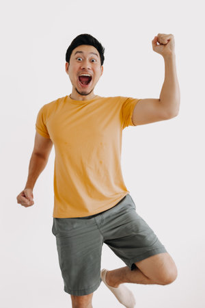 Vertical half body of funny wow face asian man jumping isolated on white.の写真素材
