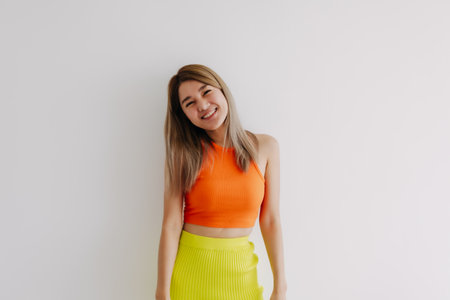 Portrait of happy cheerful asian woman in orange and lemon isolated on white.の写真素材