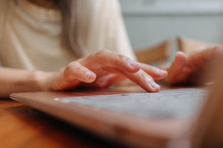 Close up of hands and fingers typing laptop keyboard. Working online in cafe.の写真素材