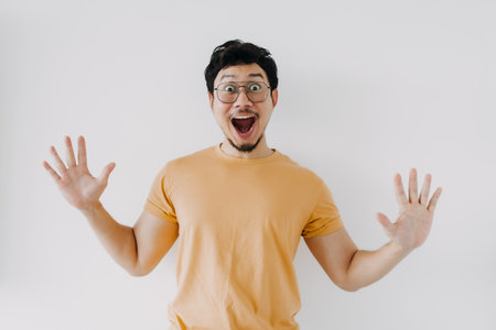 Wow and happy surprised face of asian man in yellow t-shirt isolated on white.
