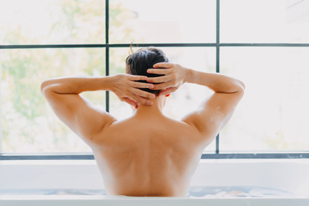 Back of asian man showering in the bathtub in the bathroom.