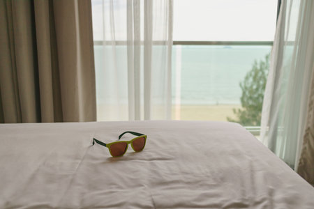 Sunglasses left on the bed in the hotel. Concept of traveling and vacation. High quality photo