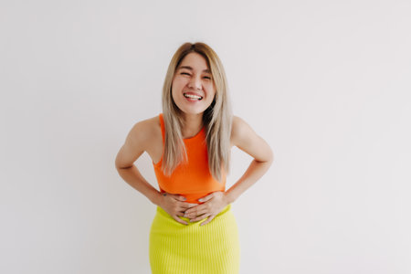 Happy cheerful cute asian woman in orange and green isolated on white.の写真素材